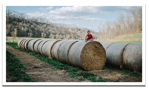 Boy sitting on hay bales in Cashton, WI
